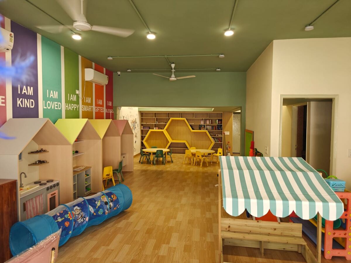 Preschool reading corner with wooden playhouses and a striped shop canopy