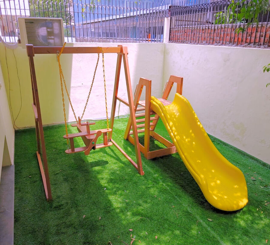 Outdoor play area with swings and a yellow slide