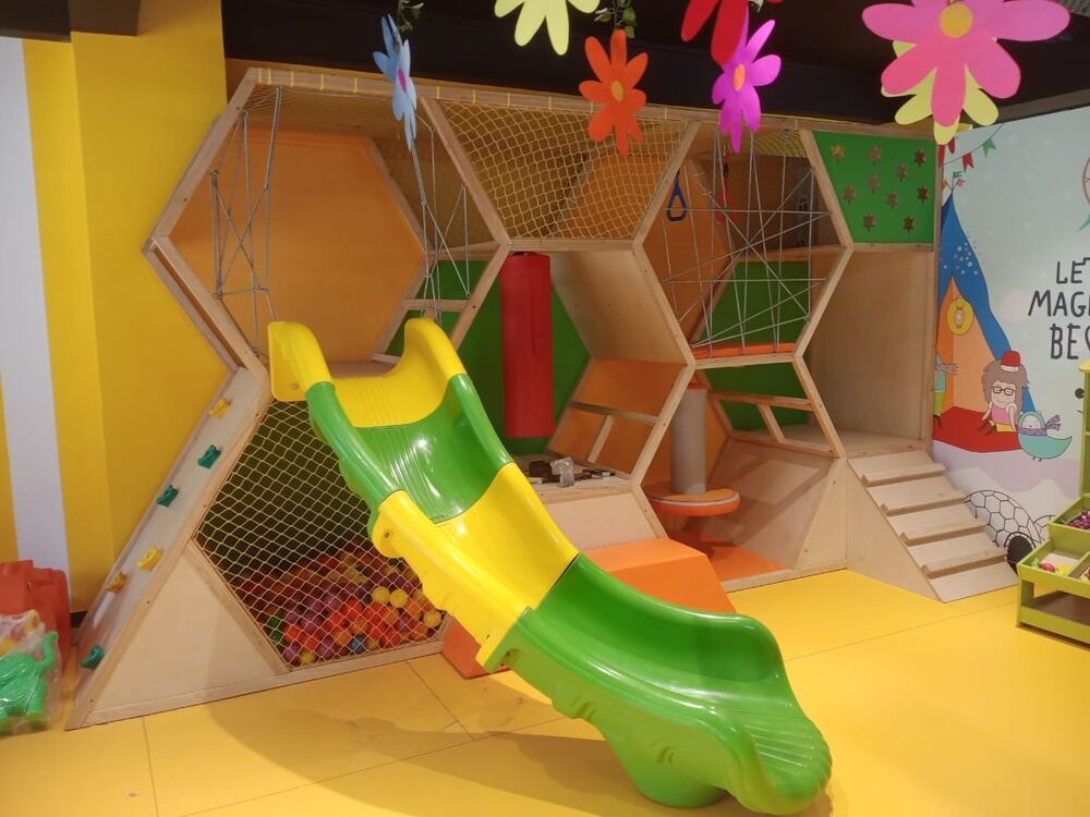 Hexagon climbing frame with a green slide and ball pit